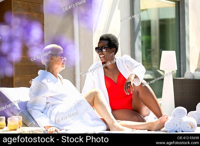 Senior women friends relaxing on sunny summer hotel patio