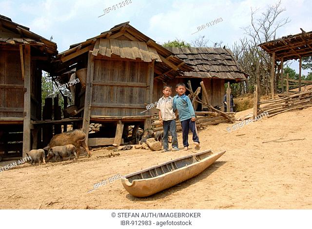Two boys in a village of the Hmong Ethnie, remains of a bomb used as a feeding trough, Phakeo, Xieng Khuang Province, Laos, Southeast Asia
