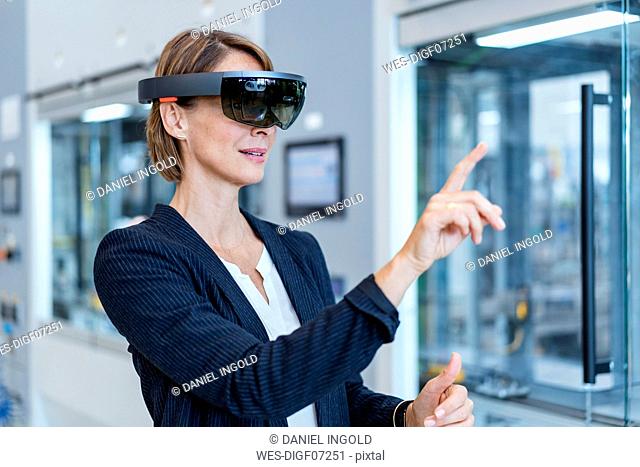 Businesswoman wearing AR glasses in a modern factory