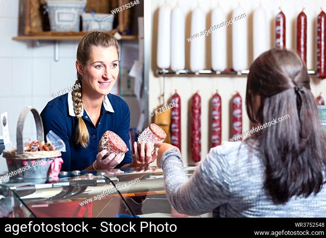 Sales lady in butchery shop serving customer selling meat