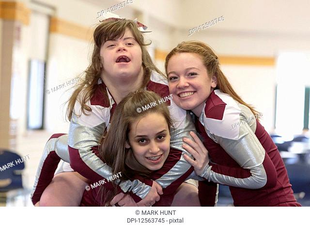 Portrait of three cheerleaders having fun, one with Down Syndrome
