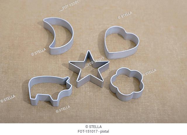 Five cookie cutters on a brown surface