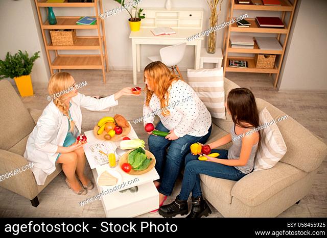 Young dietitian treating patient with healthy fruit and vegetables