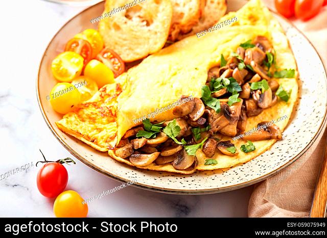 Omelet with champignons and parsley in plate on marble background. Frittata - italian omelet for breakfast or lunch