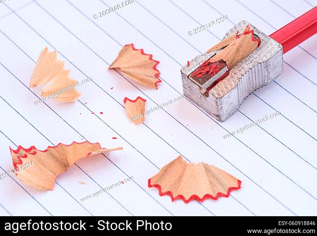 Color red art wooden pencil on a sharpener and shavings. Back to school concept