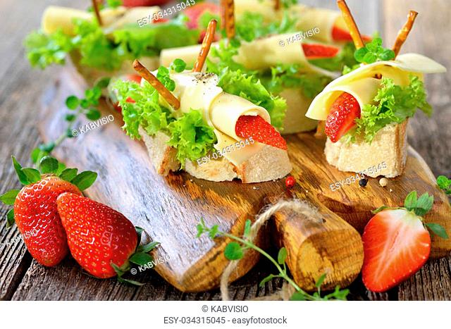 Canapes with delicious cheese rolls and strawberries on Italian ciabatta bread with lettuce leaves