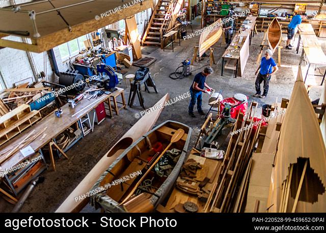 19 May 2022, Mecklenburg-Western Pomerania, Peenemünde: Together with Ursula Latus, participants of a boat-building workshop work on different wooden boat...