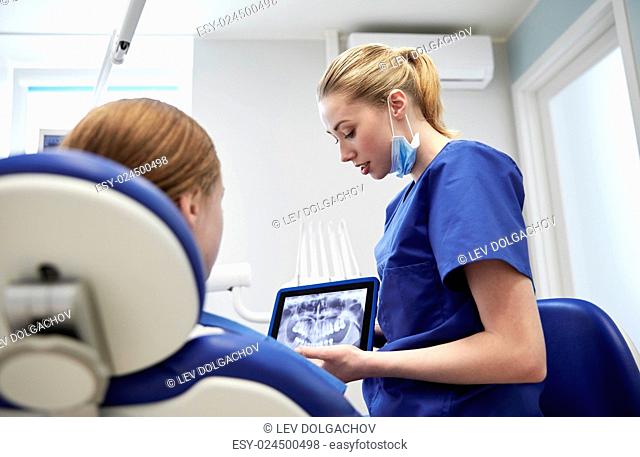 people, medicine, stomatology, technology and health care concept - female dentist showing teeth x-ray on tablet pc computer to patient girl at dental clinic...