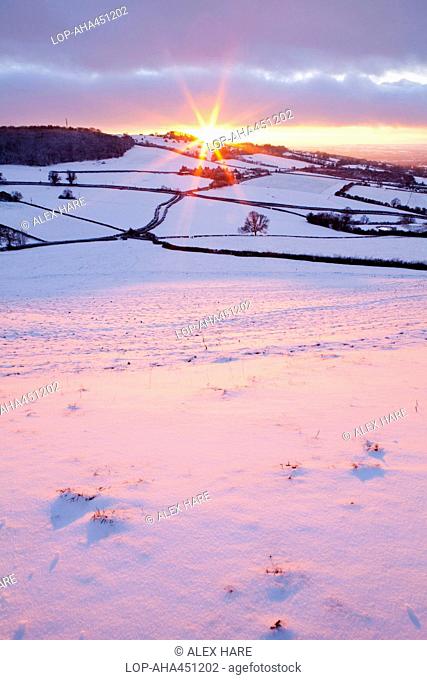 England, Bath and North East Somerset, Bath. Sunset over a snow covered hillside near Bath