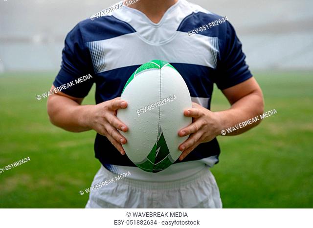 Caucasian male rugby player holding a rugby ball in stadium