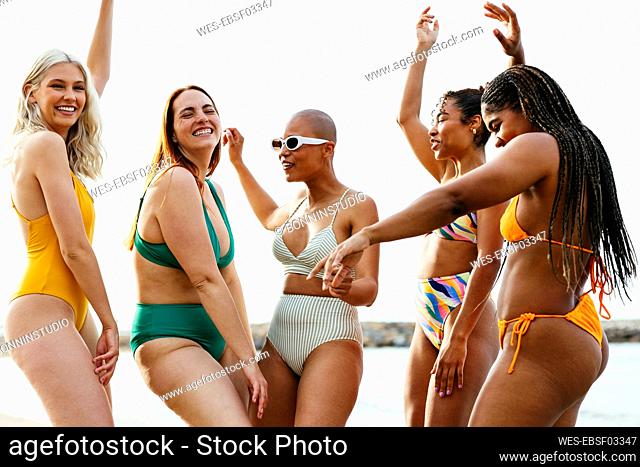 Carefree friends in swimwear dancing at beach