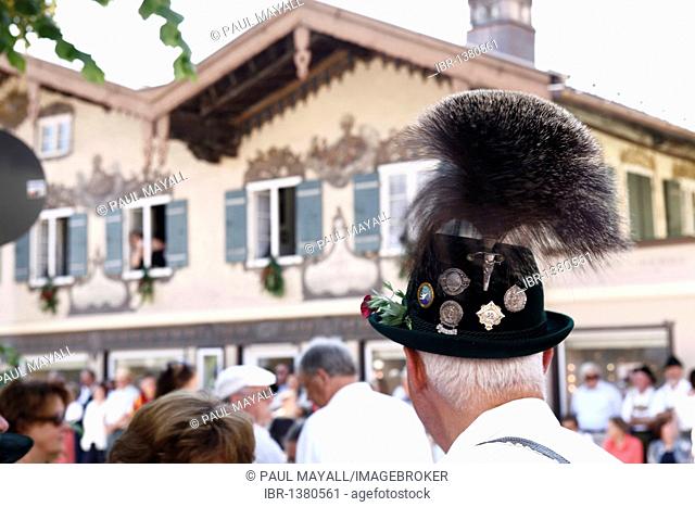 Man with a Gamsbart on his hat, Bavarian architecture behind, Prien, Chiemgau, Upper Bavaria, Germany, Europe