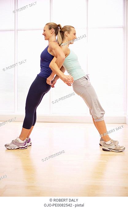 Women standing back to back in fitness studio