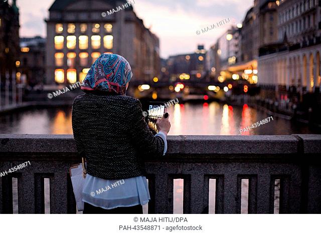 A woman with headscarf photographes the Alsterarkaden at the Alster river in Hamburg, Germanym', 15 October 2013. Photo: Maja Hitij/dpa | usage worldwide
