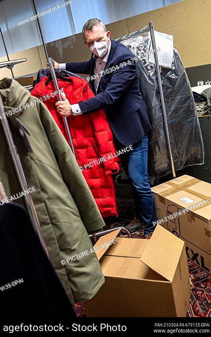 02 March 2021, Bremen: Jens Ristedt sorts through unsold winter clothing in the warehouse of his fashion store. Spring is coming