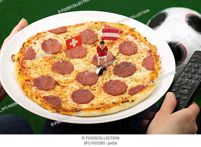 Salami pizza with flags and football figure