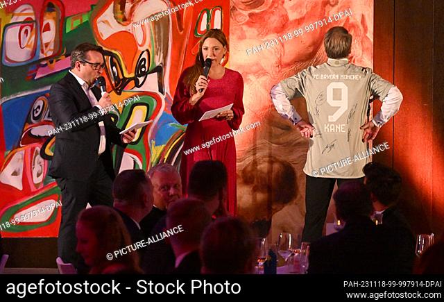 18 November 2023, Bavaria, Munich: Patrick Lindner (r), singer, stands on stage next to Simone Ballack (M) and Falk Raudies (l) with an FC Bayern Munich jersey...