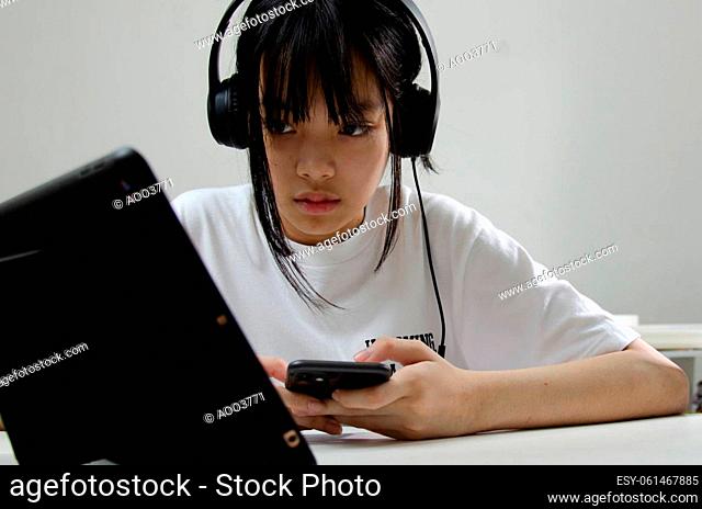 girl wearing headphones studying online with computer laptop and listen to relaxing music or play internet social media at home