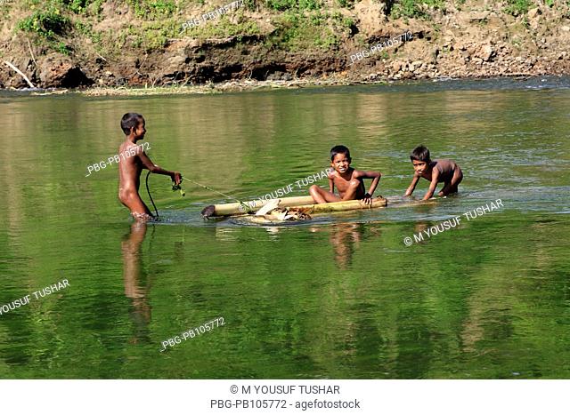 Tribal children playing with banana raft at the Sangu river Bandarban, Bangladesh December 2009