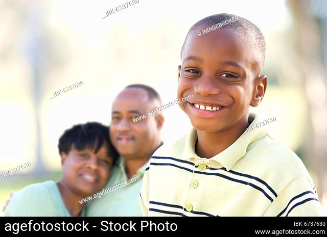 Handsome african american boy with proud parents standing by in the park