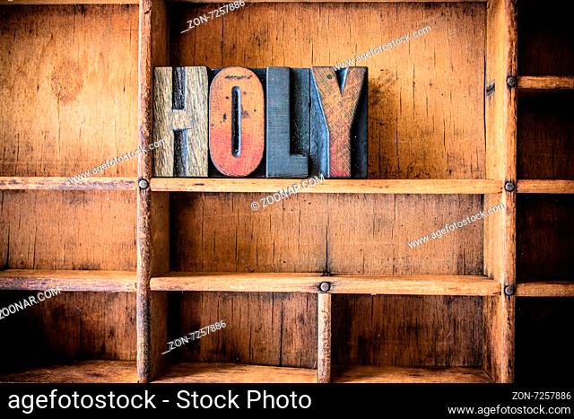 The word HOLY written in vintage wooden letterpress type in a wooden type drawer