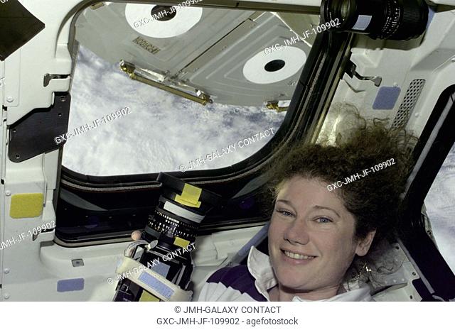 Astronaut Susan J. Helms, STS-101 mission specialist, prepares to take still photos through overhead windows on the aft flight deck of the Space Shuttle...