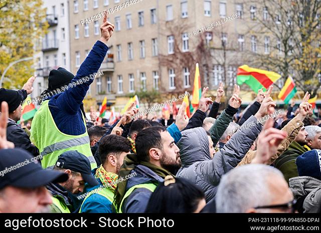 18 November 2023, Berlin: Demonstrators at Oranienplatz show the Victory sign and wave yellow-red-green flags. The demonstration by Kurds entitled ""Lift the...