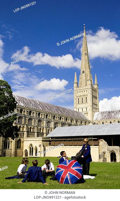 Pupils from Norwich School relax on the grass in front of Norwich Cathedral