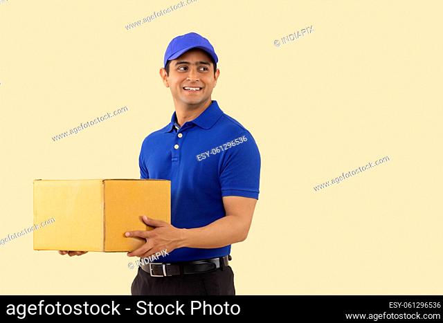 Portrait of a courier delivery boy with holding carton box in hand