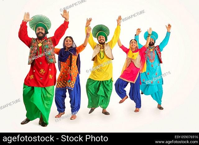 A Troupe of Punjabi Folk Dancers performing a dance step with hands up in the air