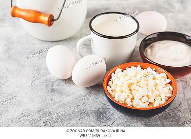 Granulated cottage curd, sour cream and cup of milk on light background