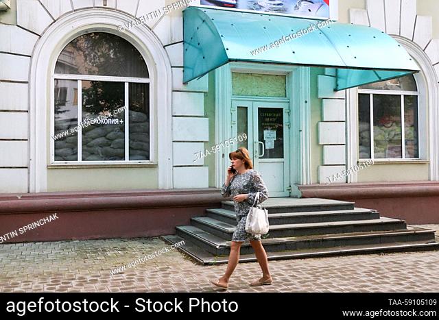 RUSSIA, DONETSK - MAY 15, 2023: A woman walks past windows protected with sandbags. The Donetsk People’s Republic has acceded to Russia as a result of a...