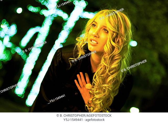 Young Caucasian female standing under yellow streetlight