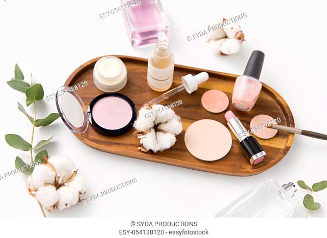 makeup, perfume and cosmetics on wooden tray