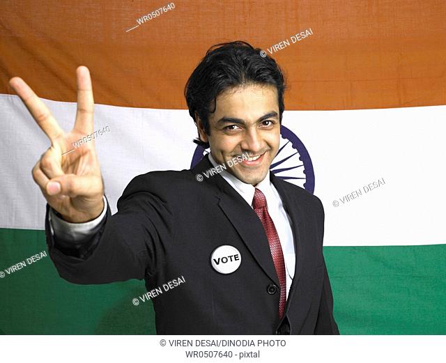 Executive showing victory sign standing in front of national flag of India MR702A