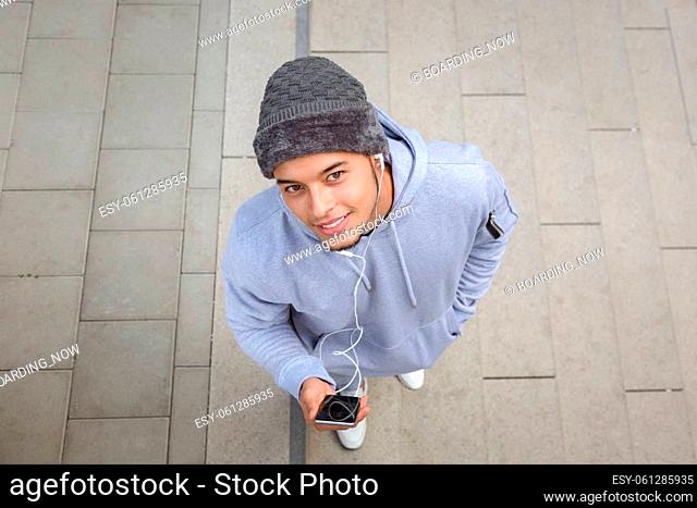 Listening to music smiling young latin man looking into camera runner sports training from above outdoor