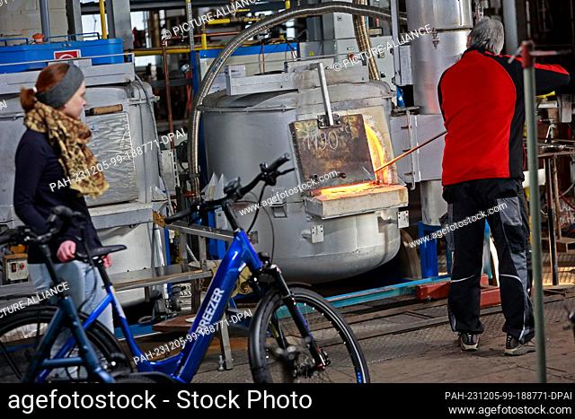 05 December 2023, Saxony-Anhalt, Derenburg: A visitor stands at the smelting furnace with a bicycle in the Harz glass factory in Derenburg