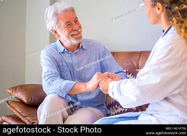 Young female doctor checking and helping senior man at his home. Doctor helping senior patient and giving care, sitting of sofa