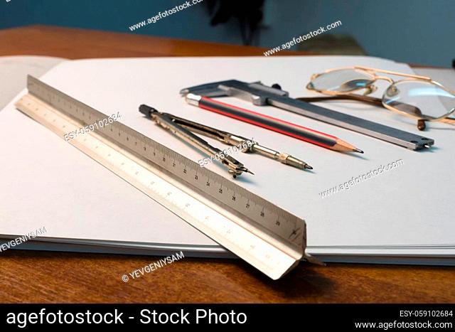 Glasses and drawing supplies are on the table in the school classroom. University academic subjects for geometry.Ruler, compass, pencil