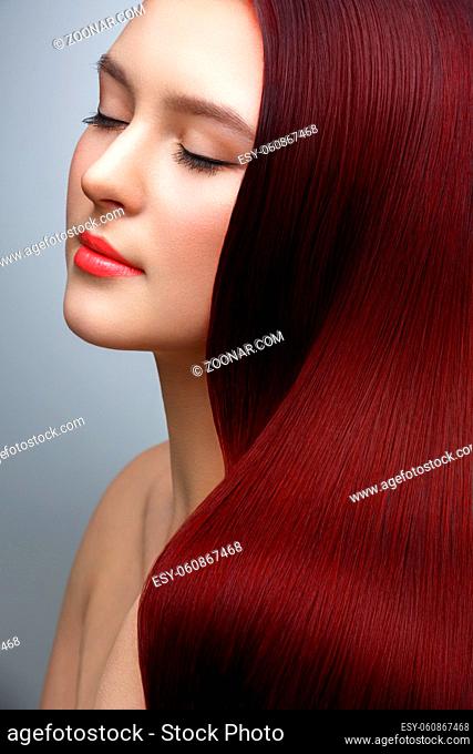 beautiful young woman with long healthy shiny hair. eyes closed. red color. studio beauty shot. copy space