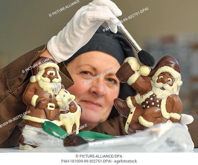 09 October 2018, Brandenburg, Hammelspring: Cornelia Grünberg, employee of Chocolaterie Hammelspring, shows chocolate Santa Clauses