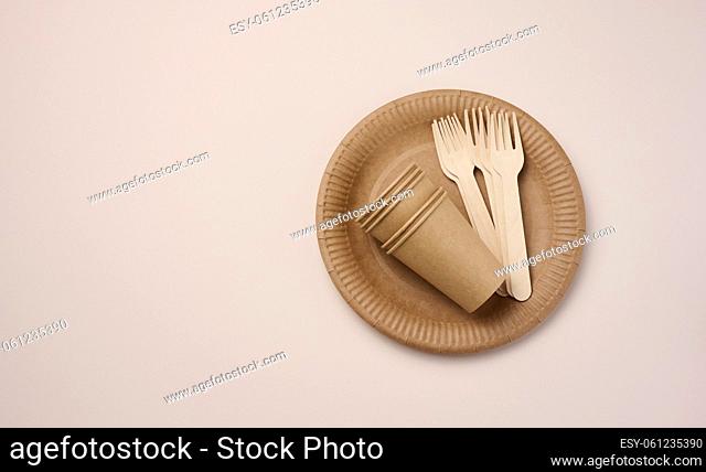Brown paper cups and plates on a beige background. Recyclable garbage, rejection of plastic, top view