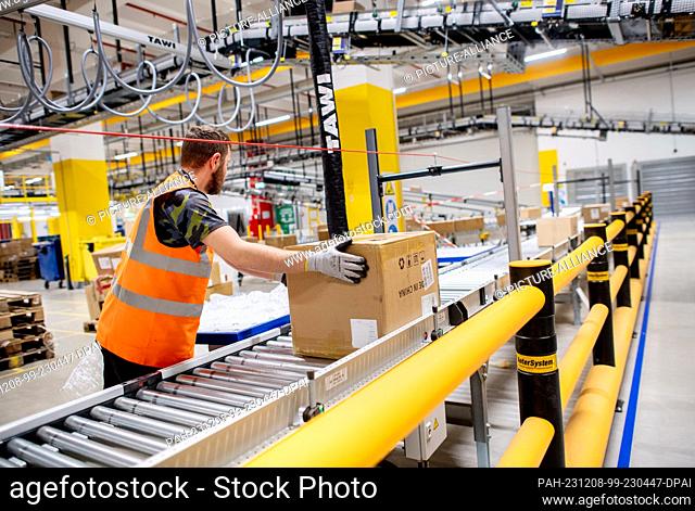 07 December 2023, Lower Saxony, Großenkneten: An employee prepares a box for storage in the incoming goods department at Amazon's new logistics center at the...