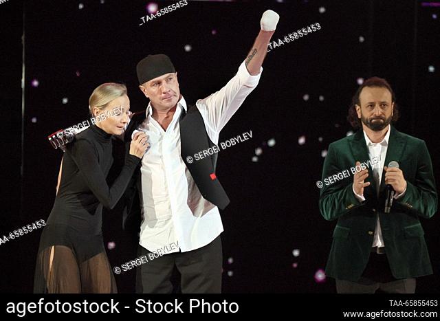 RUSSIA, MOSCOW - DECEMBER 17, 2023: Russian ice dancer Ilya Averbukh (R) claps his hands as Russian ice dancers Oksana Domnina (L) and Roman Kostomarov (C)...