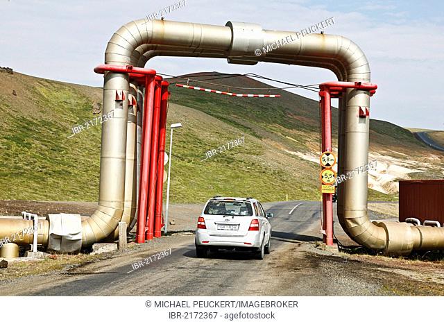 Road underneath a bridge of pipes and pipelines carrying hot water from the Kroefluvirkjun geothermal power plant, geothermal area of the Leirhnjukur fissure at...
