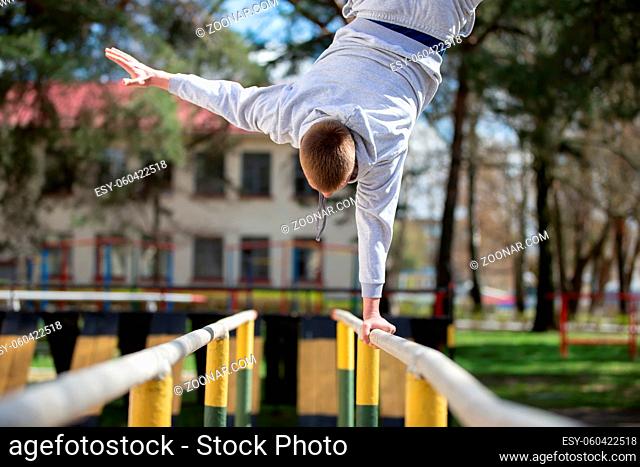 A man does exercises on uneven bars on the street. A man goes in for sports