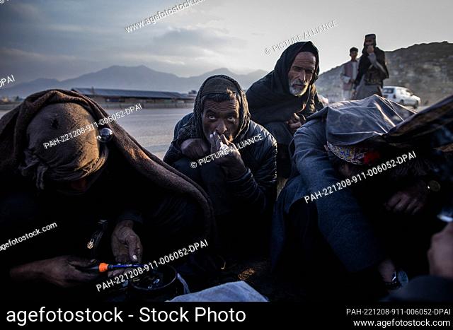 09 November 2022, Afghanistan, Kabul: Afghan men smoke drugs on the side of a highway in the outskirts of Kabul. Drug addiction has been a long standing problem...