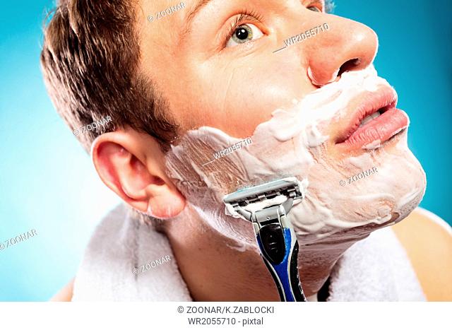 Handsome man shaving with razor