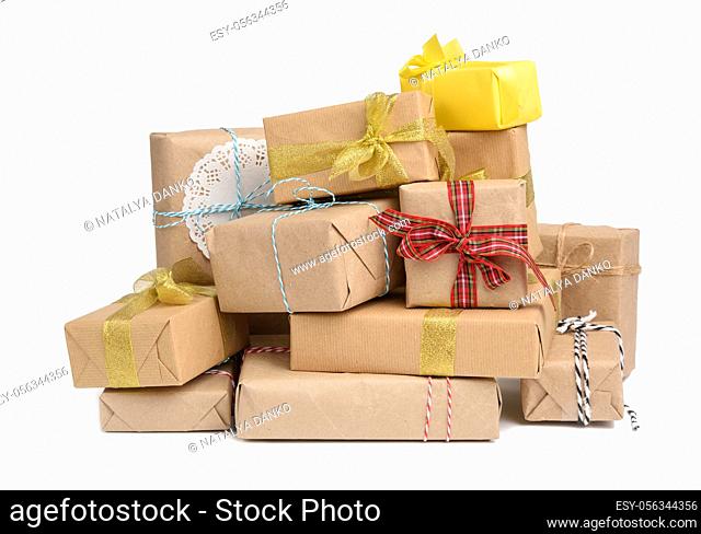 big stack of gifts wrapped in brown kraft paper and tied with silk ribbon, boxes isolated on white background, element for designer