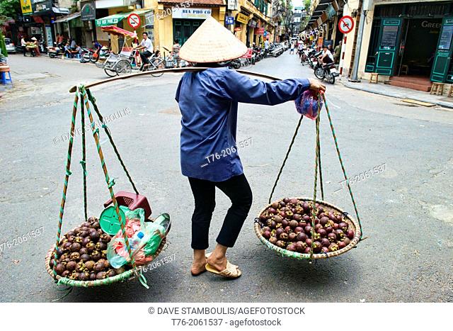 Mangosteen vendor carries her load through Hanoi, Vietnam
